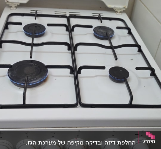 כיריים גז לבנות פועלות עם להבה כחולה בארבעת המבערים
